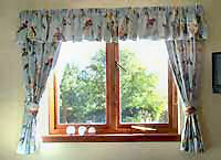 Patterned curtains and tie backs with matching gathered valance.