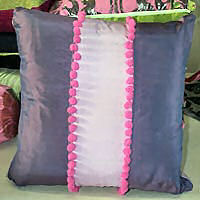 Cushion  cover with contrast and pom poms.